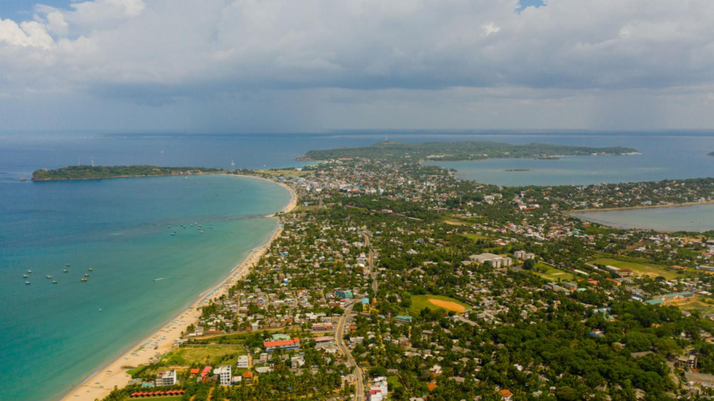 A panoramic aerial view of Trincomalee showing the cityscape, harbor, and coastline along the Indian Ocean in Sri Lanka.