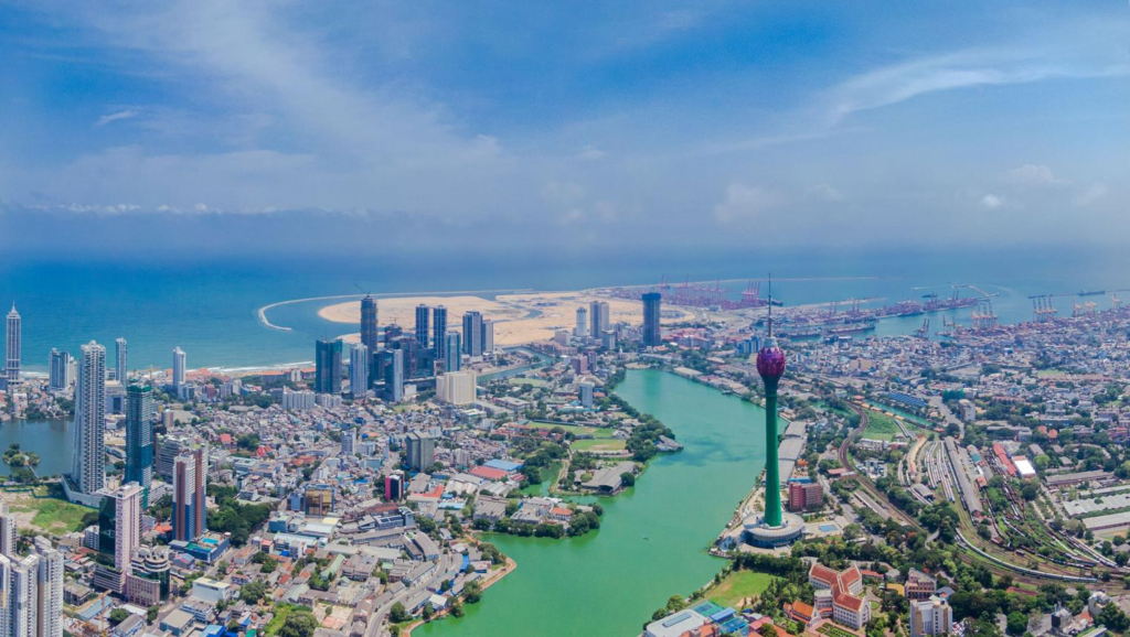 A panoramic aerial view of Colombo showing the cityscape, coastline, and port along the Indian Ocean in Sri Lanka.