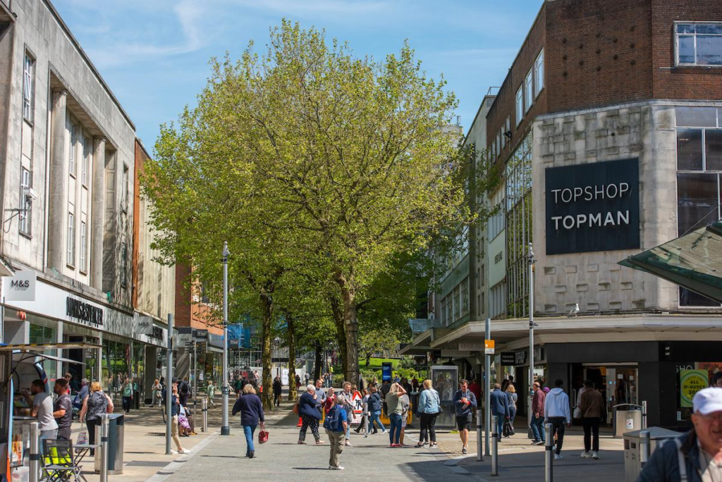 Visitors walking through streets in Swansea with shops, cafés, and pedestrian activity.