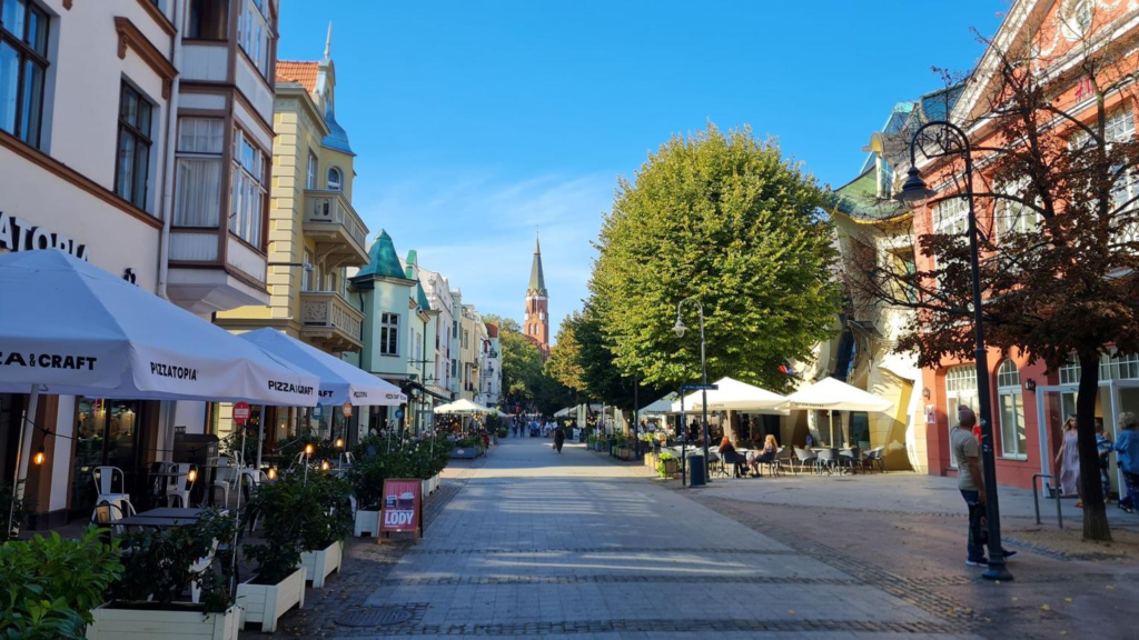 People walking through Gdynia streets with shops, cafés, and local market activity.